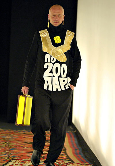 О чем будет думать мужчина в будущем сезоне у Симачева, понятно по принтам и нашивкам. Итак, его мысли касаются марихуаны, Лондона, девушек, «мира во всем мире», бензина, выпивки, фаллосов и прочих интересных вещей. Так много мыслей у героя дизайнера на самом деле оттого, что он много путешествует — один из принтов гласит «Тотал Трэвел». При этом герой неприкрыто похож на Бората Сагдиева (фильм «Борат: изучение американской культуры на благо славного Казахстана», в главной роли Саша Барон Коэн), а все присутствующие на нем вещи будто собраны со всех уголков мира и самым невообразимым образом смиксованы.  О чем будет думать мужчина в будущем сезоне у Симачева, понятно по принтам и нашивкам. Итак, его мысли касаются марихуаны, Лондона, девушек, «мира во всем мире», бензина, выпивки, фаллосов и прочих интересных вещей. Так много мыслей у героя дизайнера на самом деле оттого, что он много путешествует — один из принтов гласит «Тотал Трэвел». При этом герой неприкрыто похож на Бората Сагдиева (фильм «Борат: изучение американской культуры на благо славного Казахстана», в главной роли Саша Барон Коэн), а все присутствующие на нем вещи будто собраны со всех уголков мира и самым невообразимым образом смиксованы.